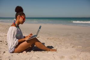 AANWP Remote Practice - Board Certified Digital Wellness Consultation from Beach Location AANWP board certified practitioner conducting remote wellness consultation on laptop while sitting on beach demonstrating practice flexibility