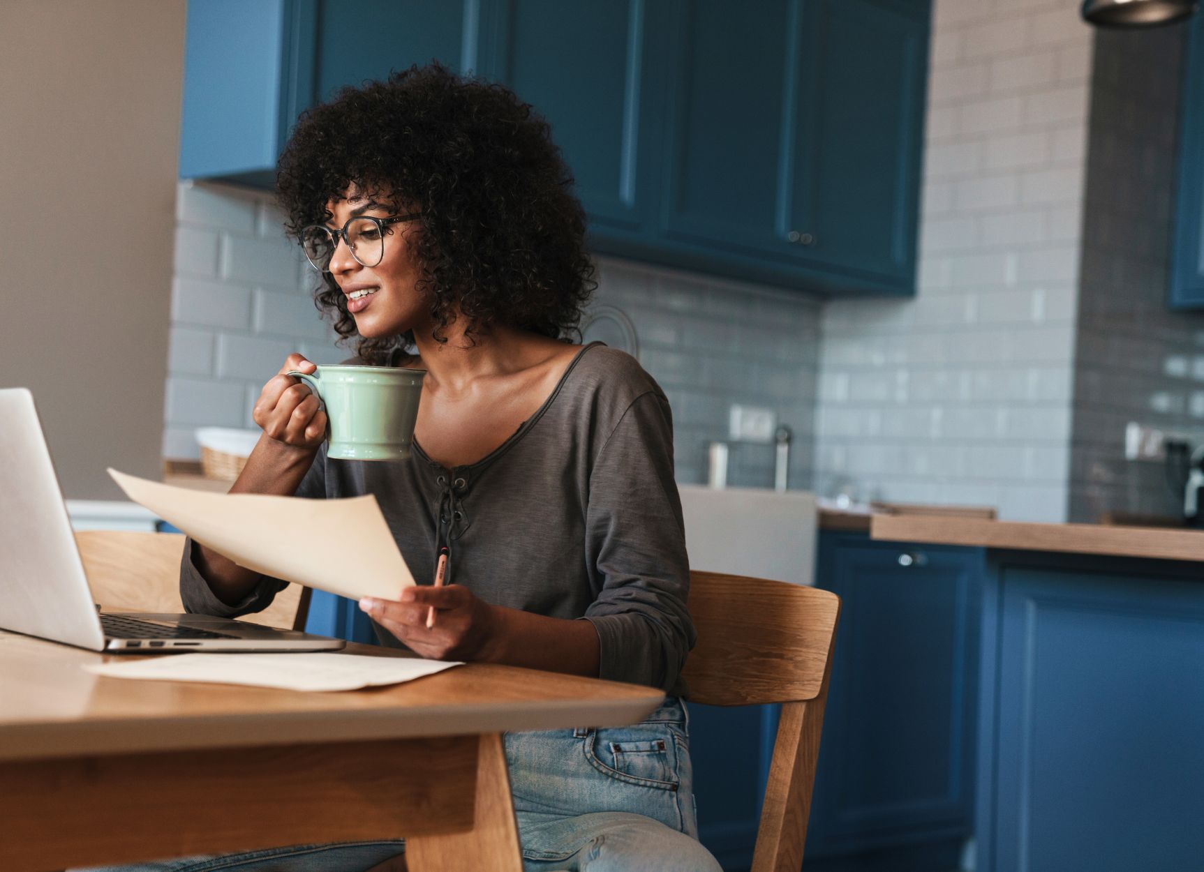 AANWP board certified natural wellness practitioner working from home kitchen with laptop and herbal tea